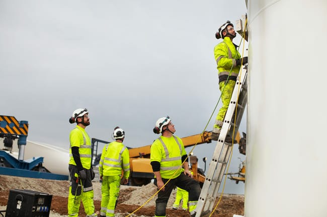A group of construction workers working on a wind turbine.