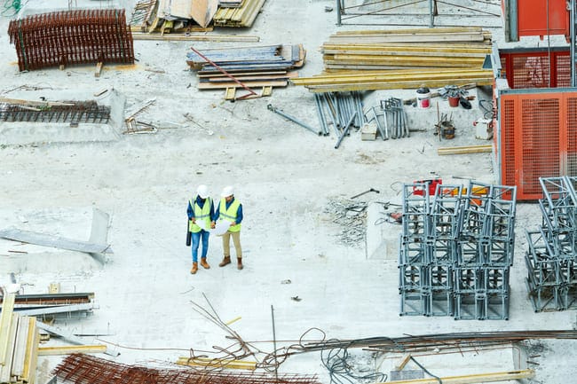 Two construction workers standing on a construction site.