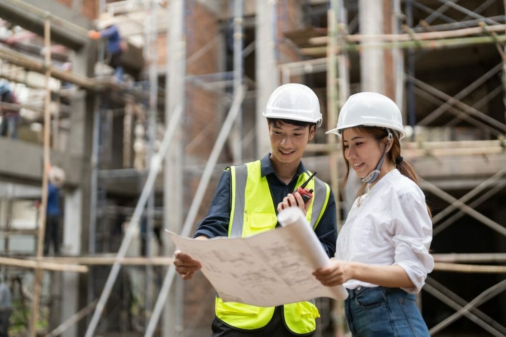Two construction workers looking at blueprints at a construction site.