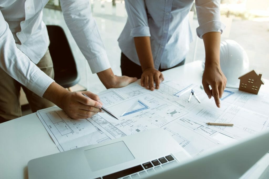 A group of people looking at blueprints on a table.