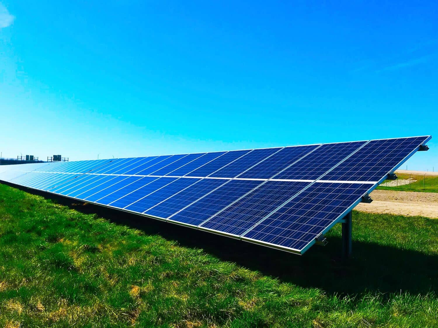 Solar panels in a field under a blue sky.