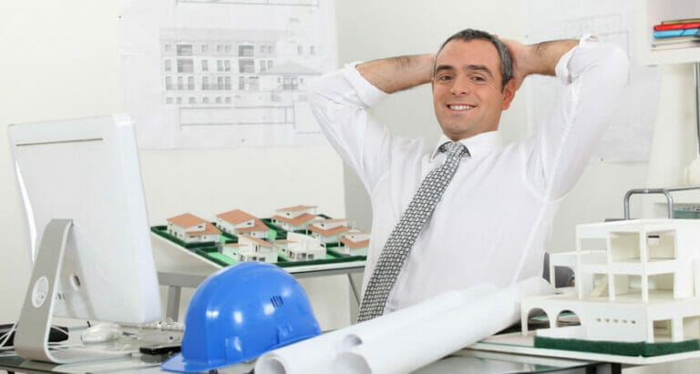 A civil engineer with a hard hat in front of a model of a building.
