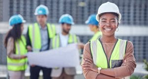 A civil engineer wearing a hard hat and a hard hat is standing in front of a group of construction workers.