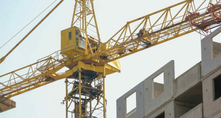 A yellow crane is on top of an innovative building.