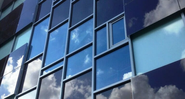 A building with photovoltaic glazing reflecting clouds in its windows.