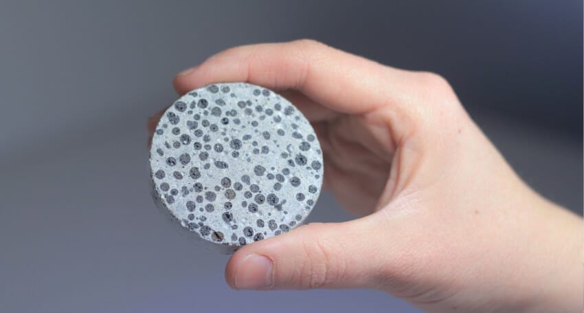 An innovative disc of self healing concrete featuring black and white polka dots held by a person's hand is showcased in this civil engineering project.