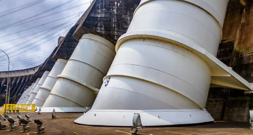 A large group of white pipes in front of the innovative Itaipu dam construction.